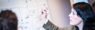 A woman is writing on a whiteboard